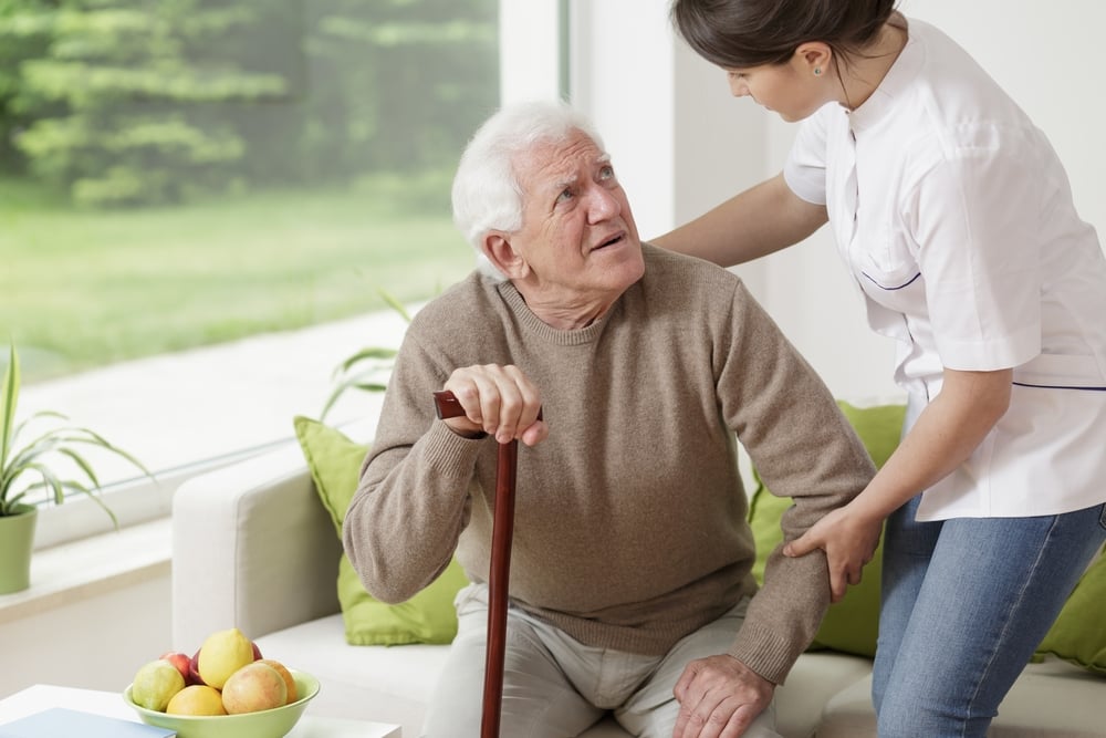 A female volunteer helping an older patient with a cane